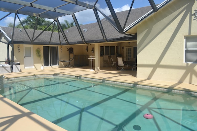 view of swimming pool featuring glass enclosure and a patio area