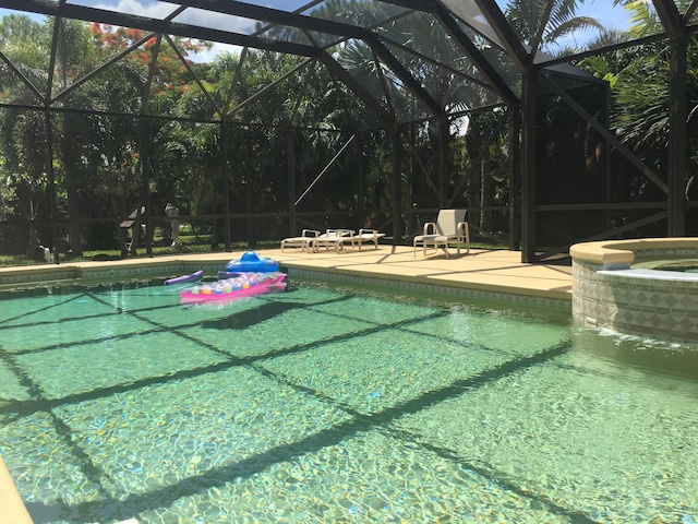 view of swimming pool with a patio area and glass enclosure