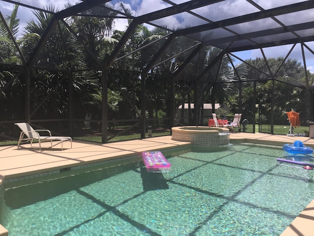 view of pool featuring a patio area, glass enclosure, and an in ground hot tub