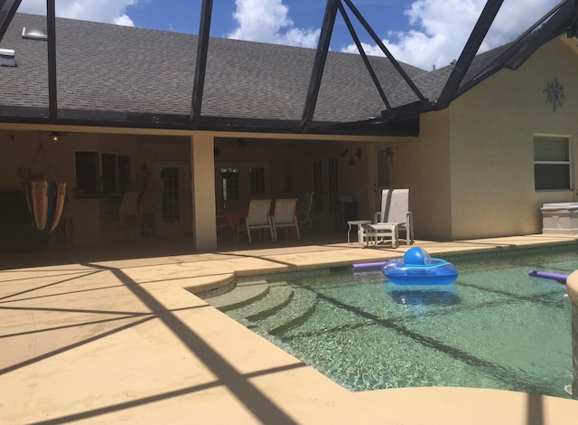 view of swimming pool featuring glass enclosure and a patio area