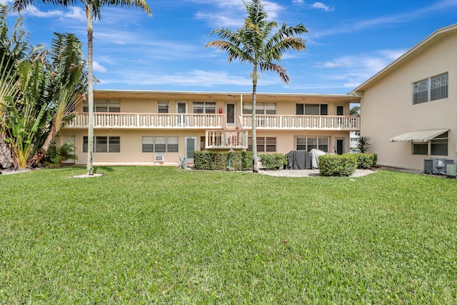 rear view of property featuring a balcony, a lawn, and central air condition unit