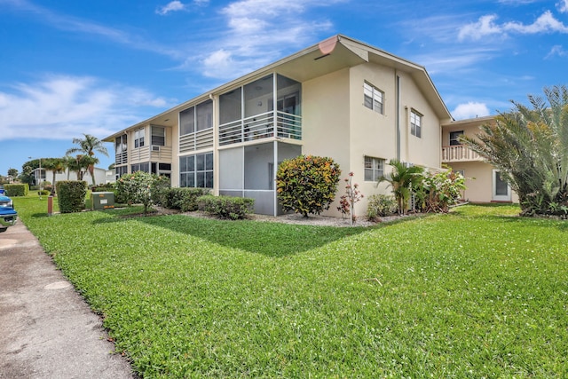 view of side of home featuring a lawn and a balcony