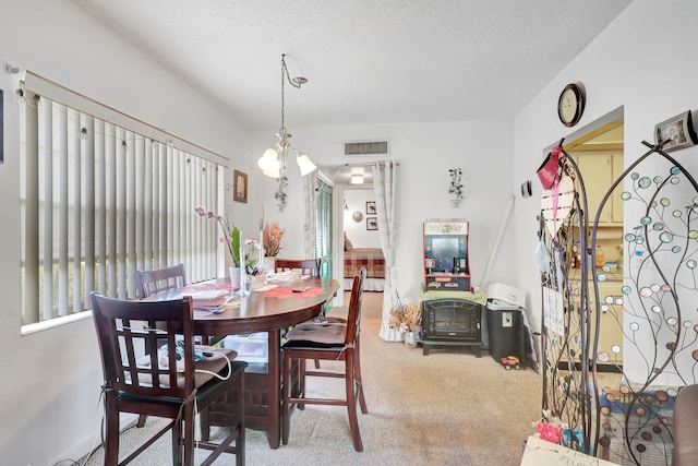 dining room featuring a chandelier, a textured ceiling, and carpet floors