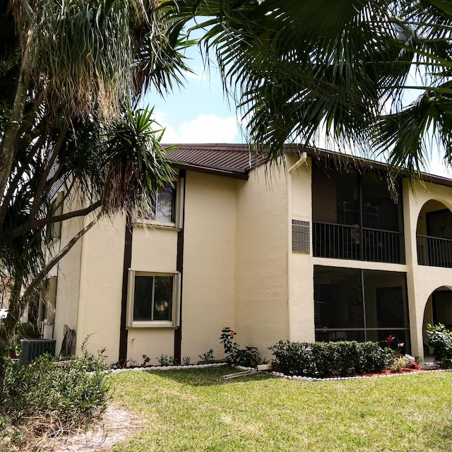 view of home's exterior featuring central AC, a lawn, and a balcony