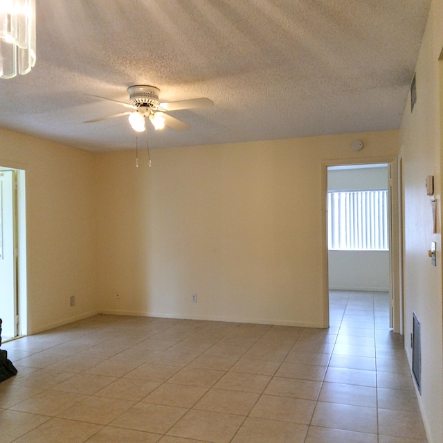 empty room with a textured ceiling, light tile patterned floors, and ceiling fan