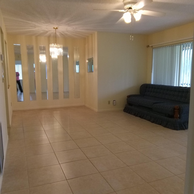 unfurnished living room with ceiling fan with notable chandelier, a textured ceiling, and light tile patterned floors