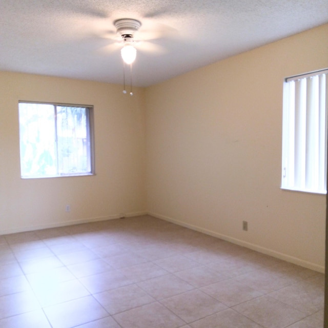 spare room with a textured ceiling, plenty of natural light, and ceiling fan