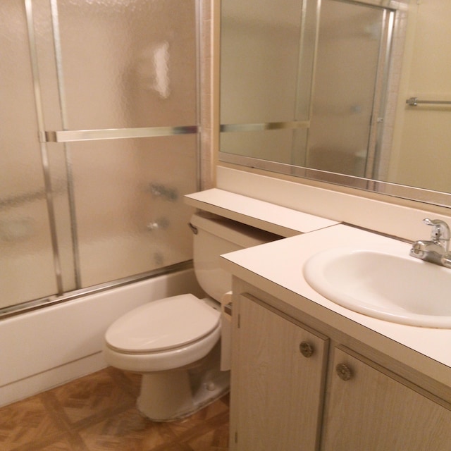 full bathroom featuring shower / bath combination with glass door, toilet, parquet flooring, and vanity