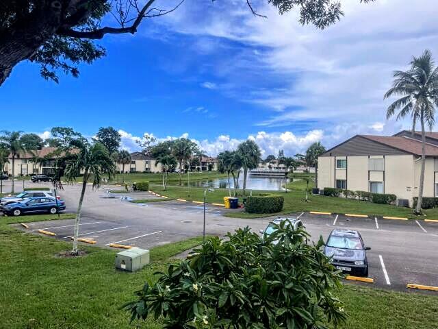 view of vehicle parking with a water view and a yard