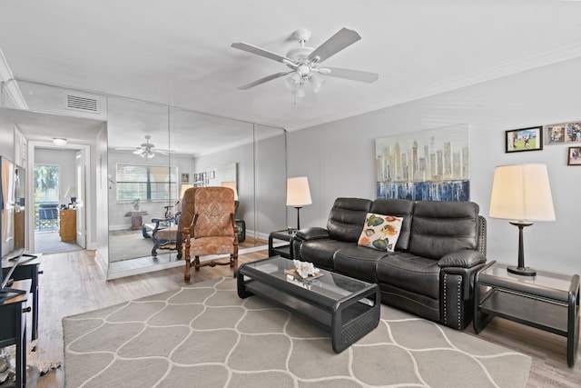 living room featuring ornamental molding, light hardwood / wood-style floors, and ceiling fan