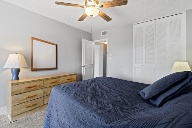 carpeted bedroom featuring a closet, ceiling fan, and a textured ceiling