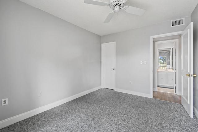 spare room with ceiling fan and dark colored carpet