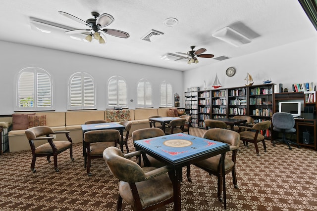 rec room with dark carpet, ceiling fan, and a textured ceiling