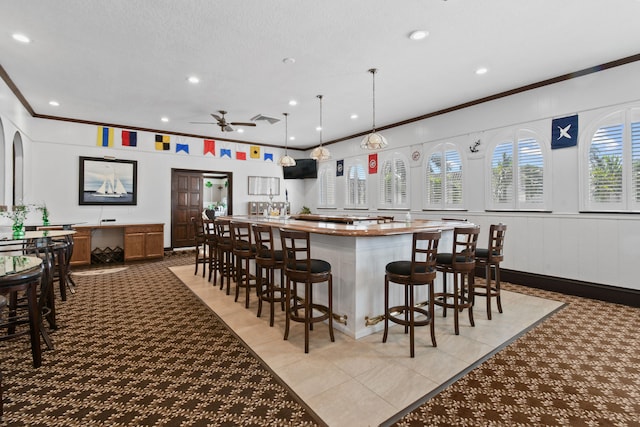 bar featuring light tile flooring, hanging light fixtures, ceiling fan, and crown molding