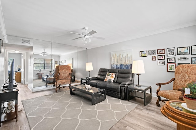 living room featuring ornamental molding, ceiling fan, and light wood-type flooring