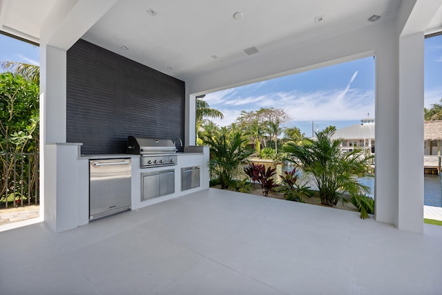 view of terrace featuring a water view, an outdoor kitchen, and grilling area