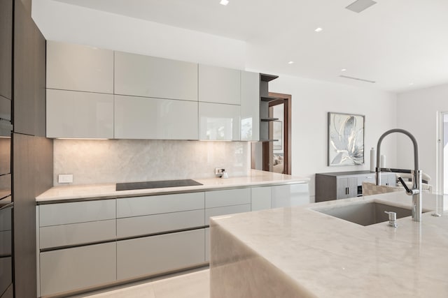 kitchen with black electric stovetop, backsplash, gray cabinets, and sink