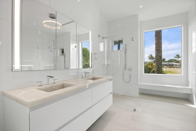 bathroom with oversized vanity, tile floors, dual sinks, and tiled shower