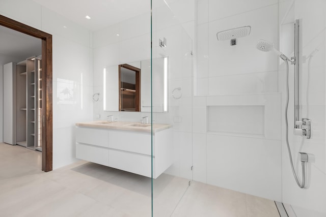 bathroom with tile floors, a tile shower, and vanity