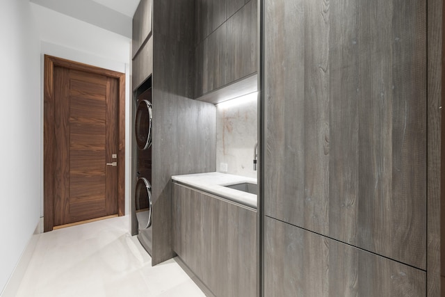 interior space featuring light tile floors and stacked washing maching and dryer