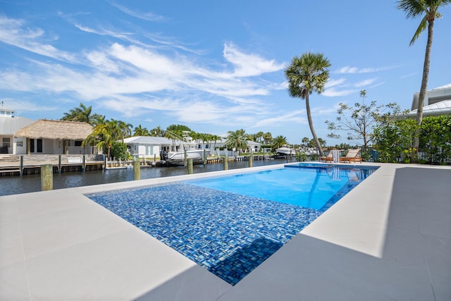 view of pool featuring a water view, a boat dock, and a patio area