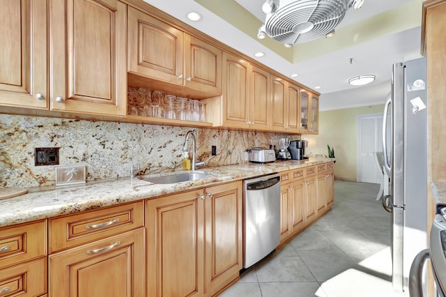 kitchen with sink, stainless steel appliances, light stone counters, backsplash, and light tile patterned floors