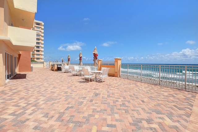 view of patio with a water view and a beach view