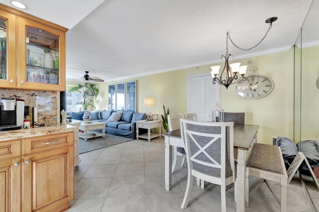 dining area with light tile patterned floors, ceiling fan with notable chandelier, and ornamental molding