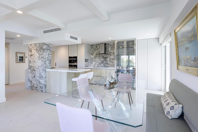 carpeted dining area with beam ceiling