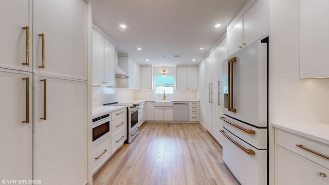 kitchen with sink, tasteful backsplash, white appliances, white cabinets, and light wood-type flooring