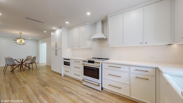 kitchen featuring white range, wall chimney range hood, light hardwood / wood-style flooring, built in microwave, and white cabinetry