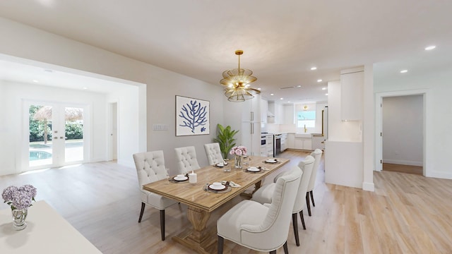 dining space featuring french doors, light hardwood / wood-style flooring, a notable chandelier, and sink