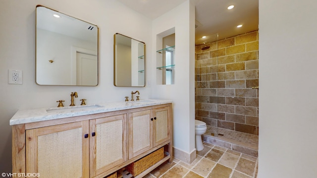 bathroom featuring vanity, toilet, and tiled shower