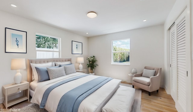 bedroom featuring a closet, light hardwood / wood-style floors, and multiple windows