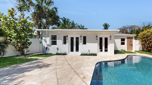 rear view of house featuring a fenced in pool, a patio, and french doors