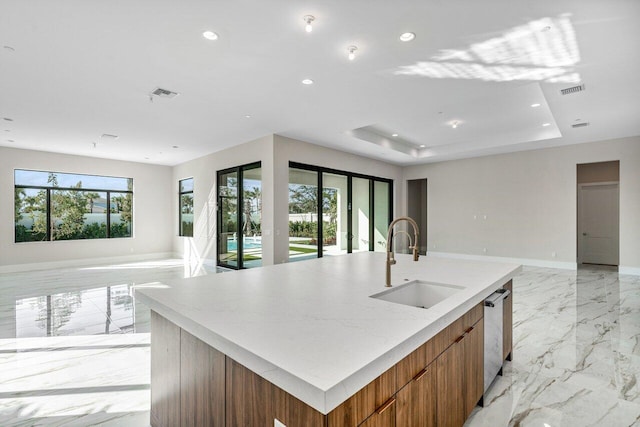 kitchen with sink, a tray ceiling, dishwasher, and a spacious island