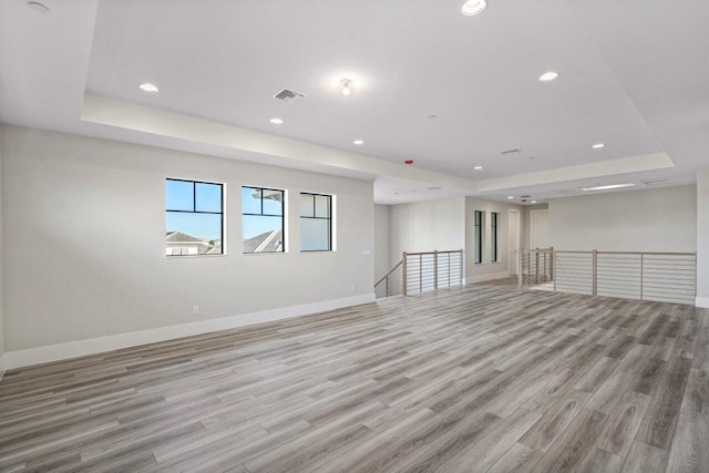 unfurnished room with light hardwood / wood-style floors and a tray ceiling