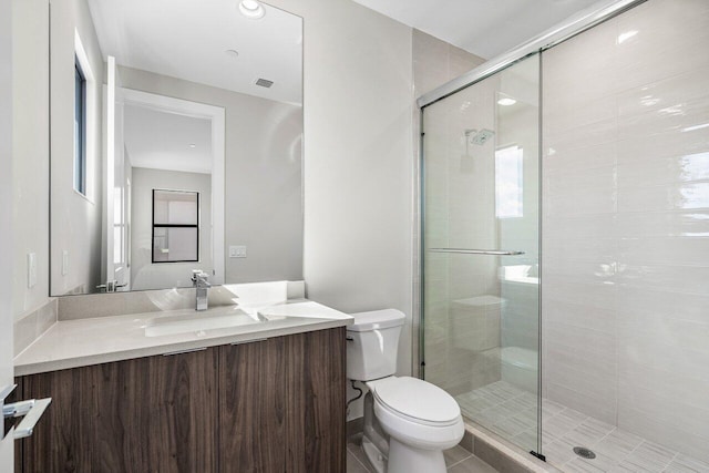 bathroom featuring vanity, a shower with door, and toilet