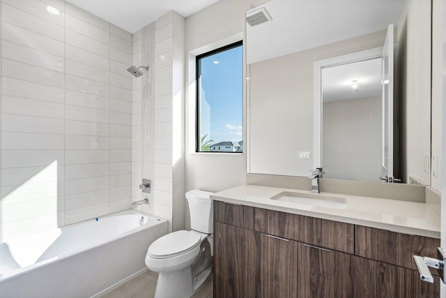 full bathroom featuring vanity, tiled shower / bath, and toilet