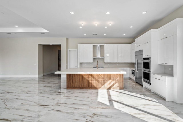 kitchen with white cabinetry, backsplash, stainless steel appliances, and a spacious island