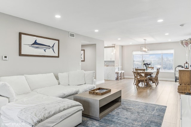 living room featuring a chandelier and light hardwood / wood-style floors