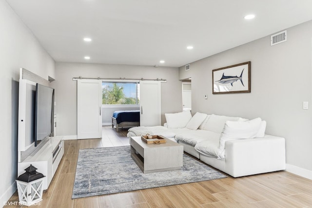 living room featuring a barn door and light hardwood / wood-style floors