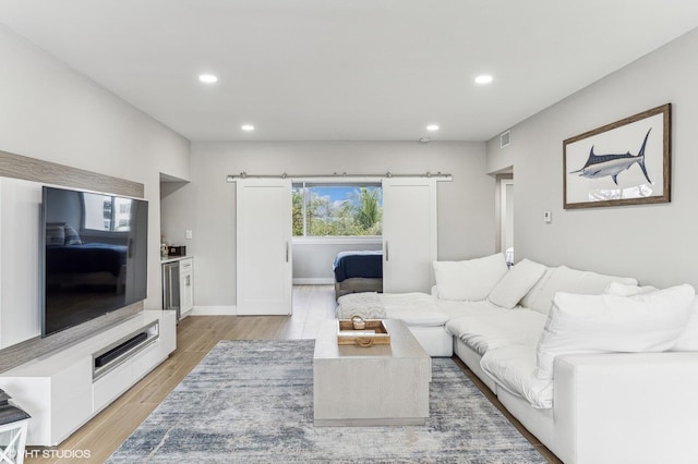 living room with a barn door and light wood-type flooring