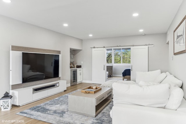 living room featuring a barn door, beverage cooler, and light hardwood / wood-style floors