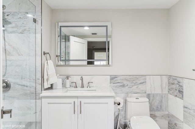 bathroom featuring tile walls, toilet, a tile shower, and vanity