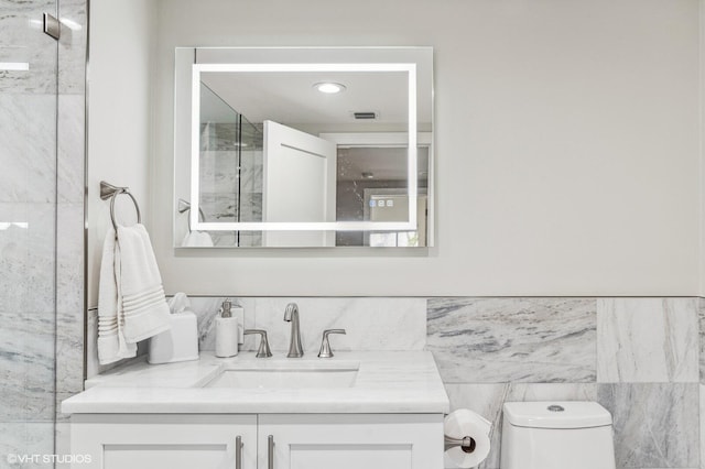 bathroom featuring tile walls, oversized vanity, toilet, and backsplash