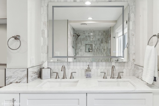 bathroom featuring tasteful backsplash, tiled shower, tile walls, and dual bowl vanity