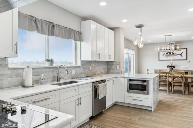 kitchen featuring white cabinets, hanging light fixtures, sink, and stainless steel appliances