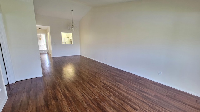 empty room with a chandelier, dark wood-type flooring, and high vaulted ceiling