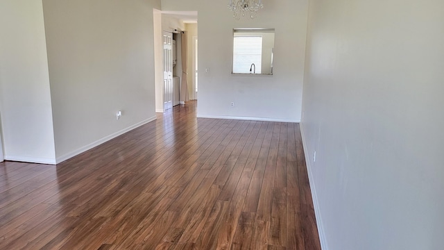 spare room with a barn door, dark hardwood / wood-style floors, and an inviting chandelier